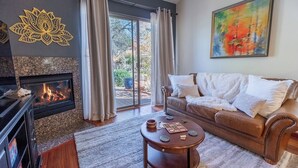 Una sala de estar con chimenea, un sofá, una mesa de centro y un cuadro en la pared.
