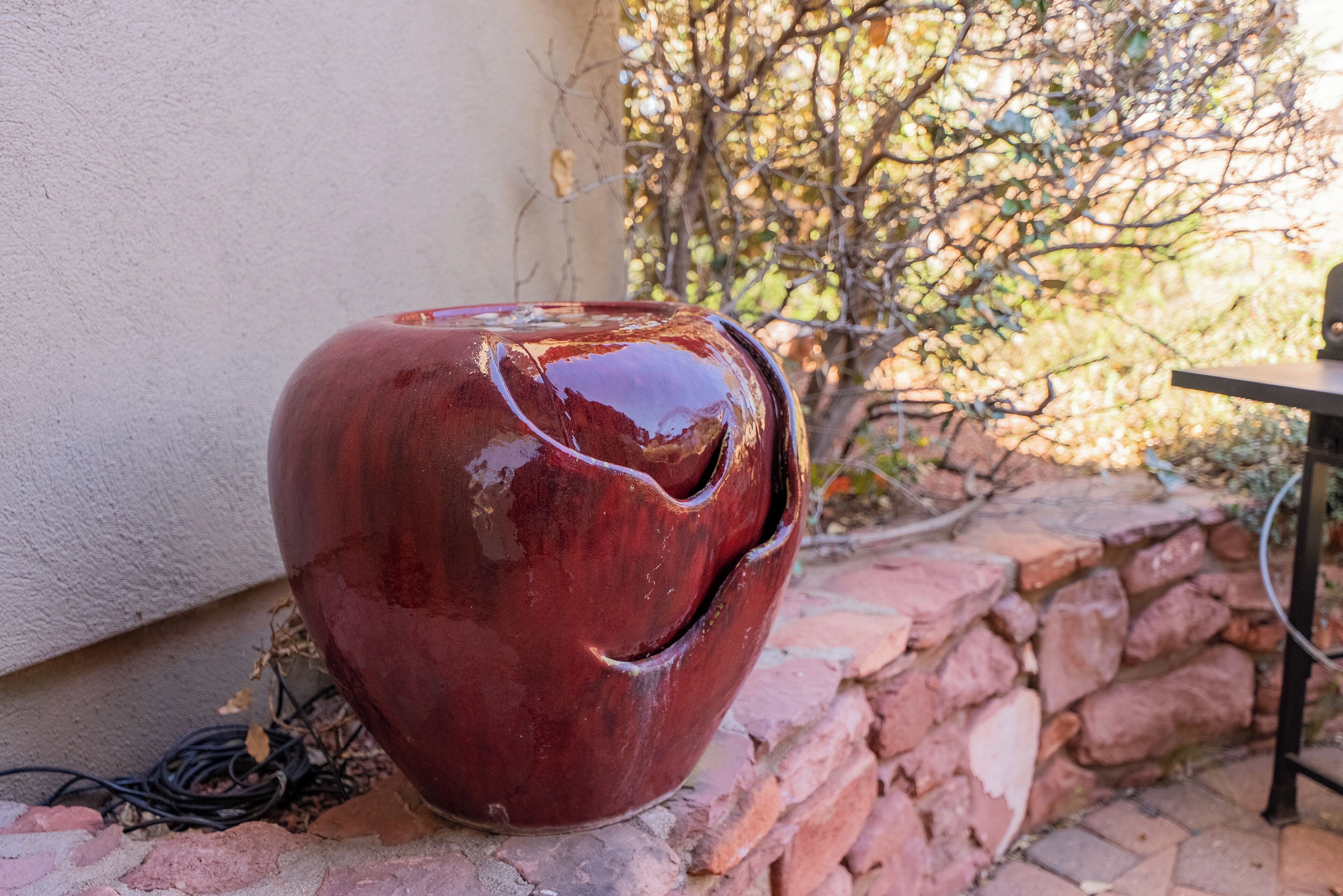 A red ceramic pot on a brick ledge near a white wall.