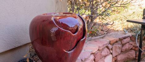 A red ceramic pot on a brick ledge near a white wall.