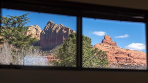 Vista de una montaña a través de una ventana, con árboles en primer plano.