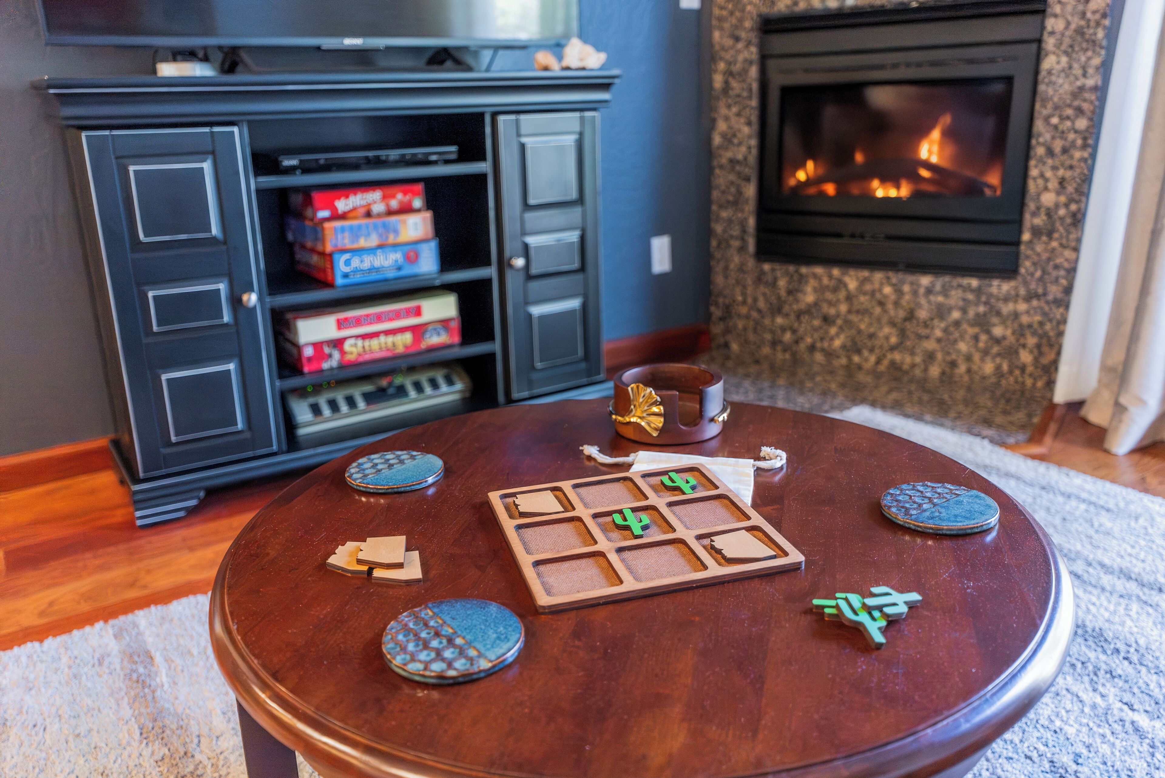 A wooden table with a board game, a television, and a fireplace in the background.