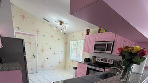 Eine Küche mit rosa Schränken, einer Granit-Arbeitsplatte und einem Edelstahlbackofen.