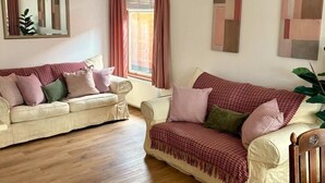 Ein Wohnzimmer mit zwei Sofas, Holzboden, einem Spiegel und abstrakter Wandkunst.