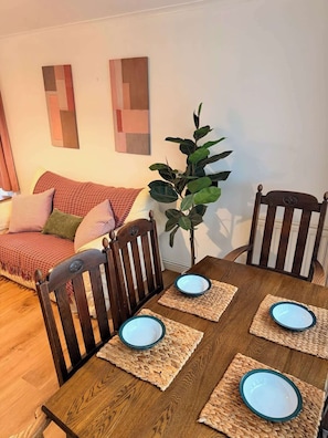 Un coin repas avec une table en bois dressée pour quatre personnes, entourée de chaises en bois.