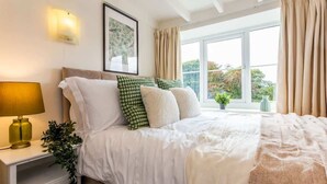 Une chambre à coucher avec un lit, une lampe de chevet et une fenêtre avec des rideaux.