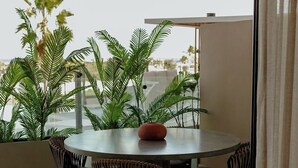 A round table with four chairs, a vase, and large green plants in a modern indoor space with a view.