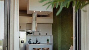 A modern kitchen with a central island, bar stools, and a dining area with a sofa and coffee table.