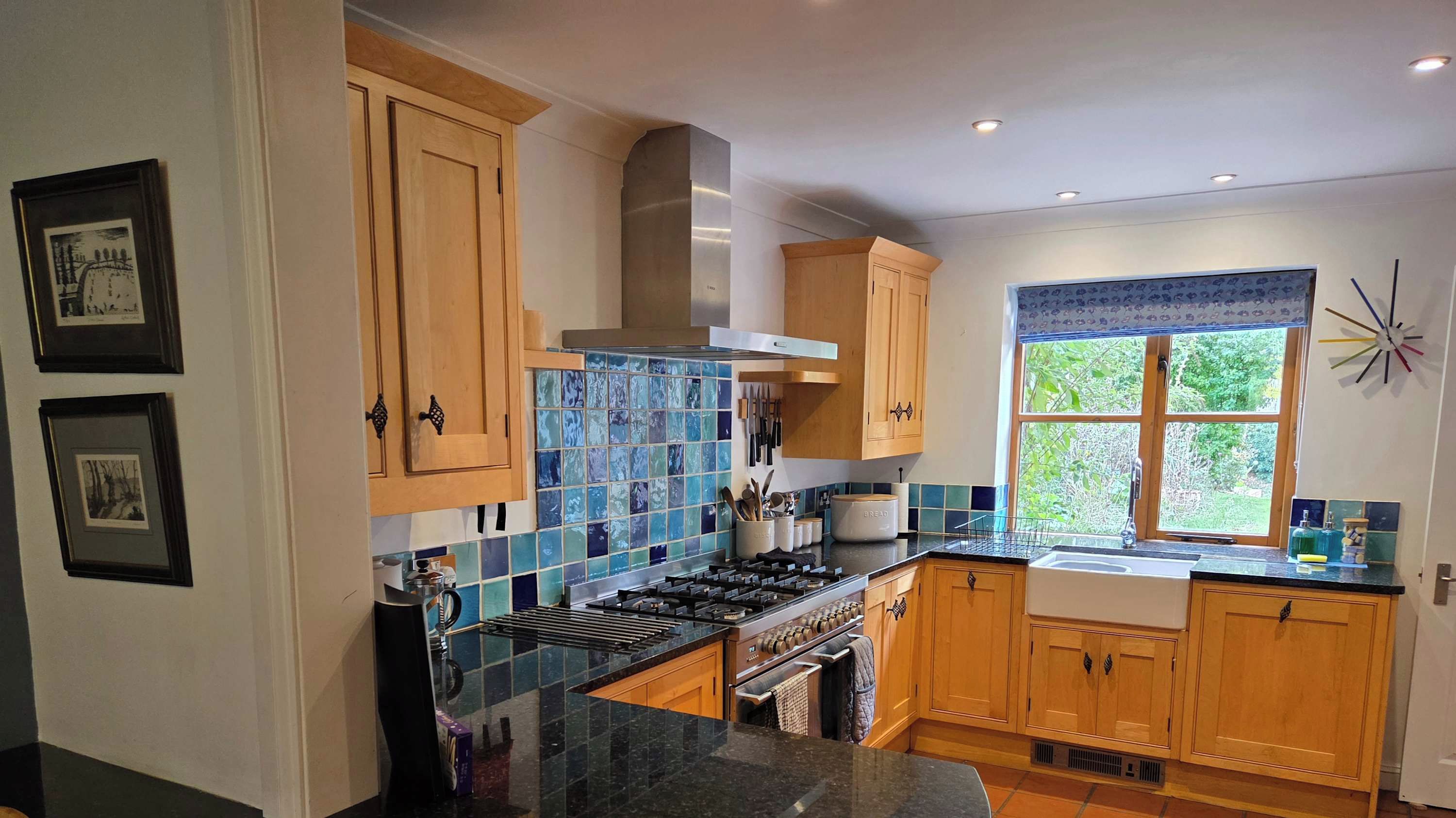A kitchen with wooden cabinets, a gas stove, and a window with a view of greenery.