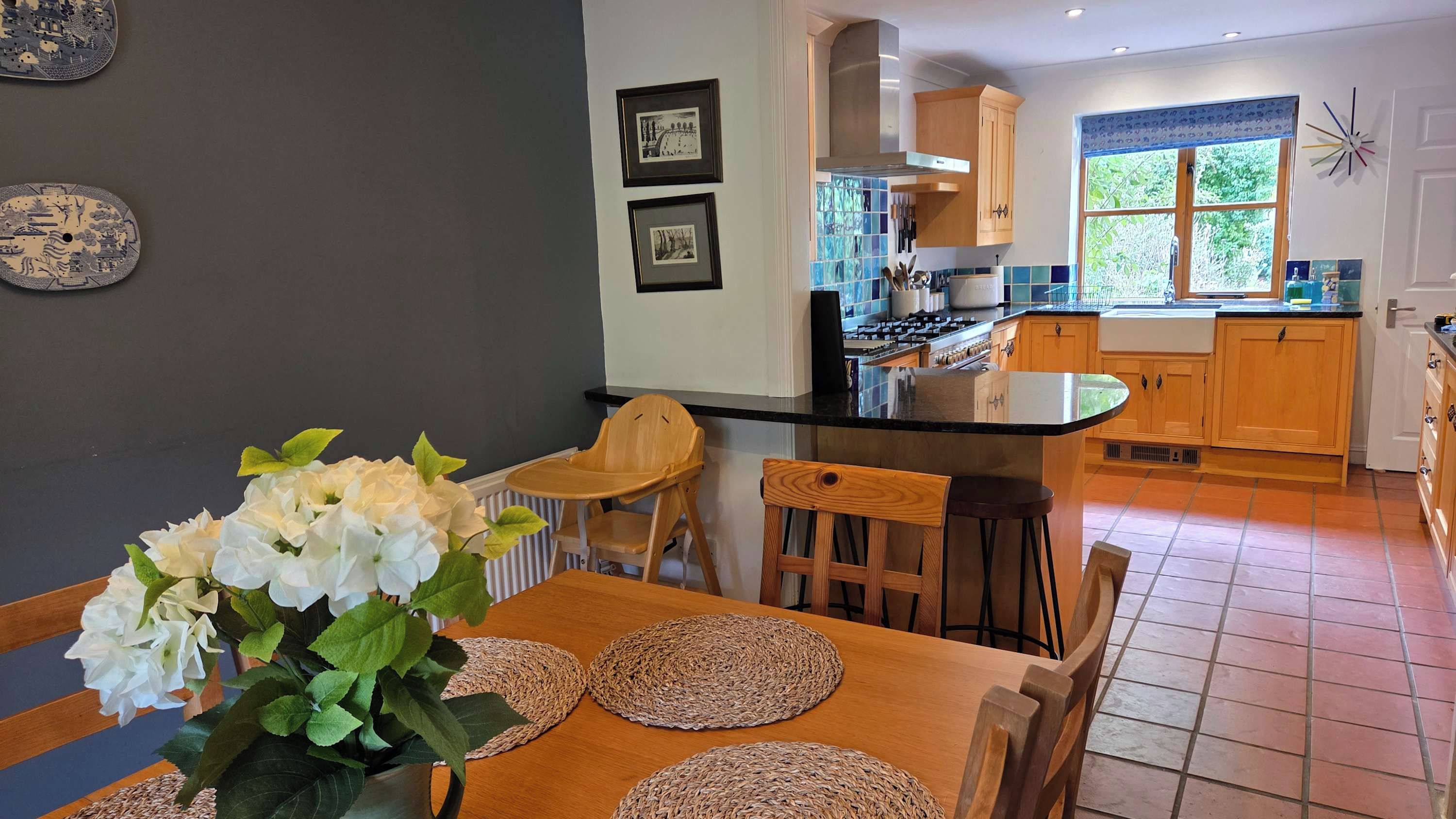 A modern kitchen with a central island, wooden cabinets, and a dining area with a table and chairs.
