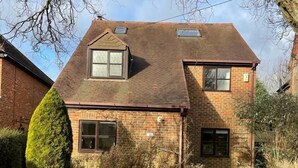 A two-story brick house with a sloped roof, a small attic window, and a front door. - Spacious Village House near Oxford with Woodburner (Horspath)