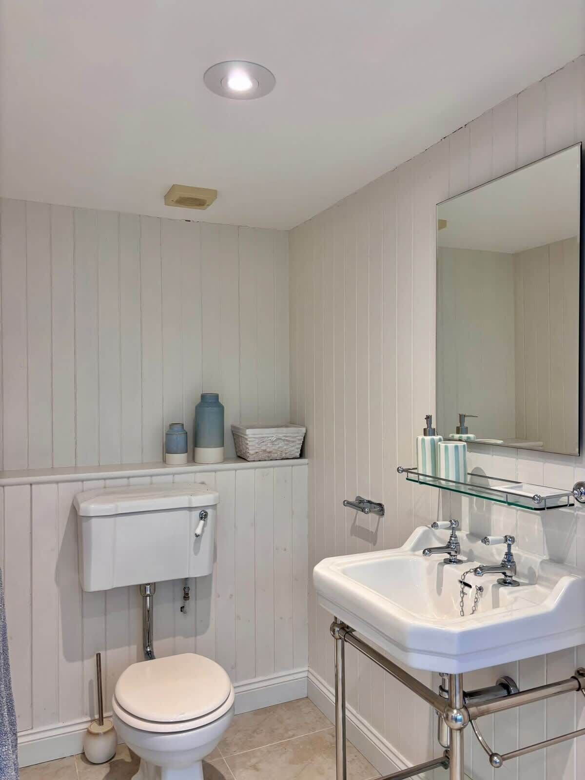 Een badkamer met toilet, wastafel en spiegel.