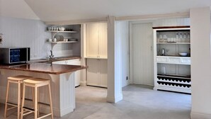 A modern kitchen with a skylight, white cabinetry, and a small bar area with stools.