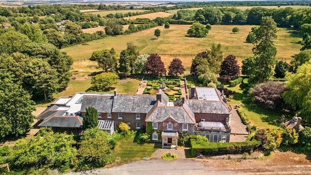 A large estate with multiple buildings, expansive green fields, and a well-maintained garden.