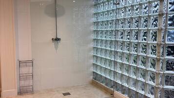 Une salle de bain moderne avec une douche à parois de verre, des murs carrelés et un étagère en métal.