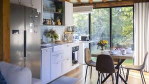 Cocina moderna con electrodomésticos de acero inoxidable, comedor con mesa y sillas, y un amplio ventanal con vistas a zonas verdes.