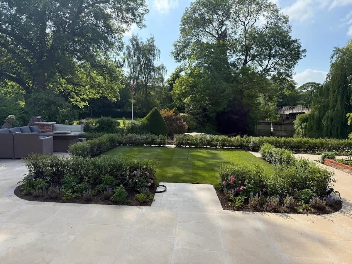 A well-maintained garden with a lawn, decorative bushes, and a small bridge.