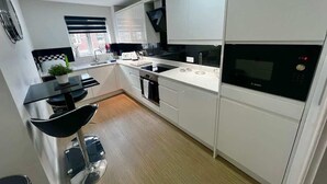 A modern kitchen with white cabinets, a black countertop, and a Bosch microwave.