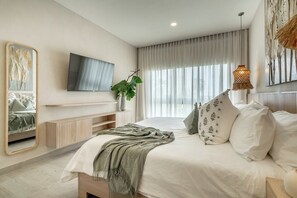 Une chambre à coucher moderne avec un grand lit, un téléviseur fixé au mur et une grande fenêtre avec des rideaux.
