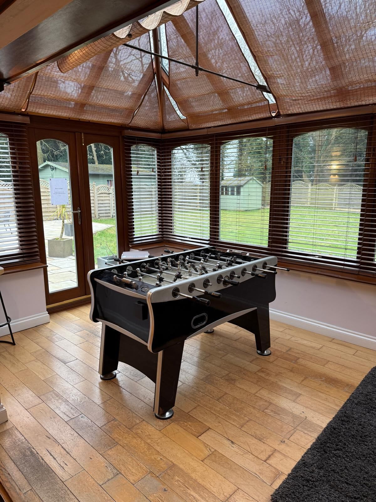 A foosball table in a room with large windows and a wooden ceiling.