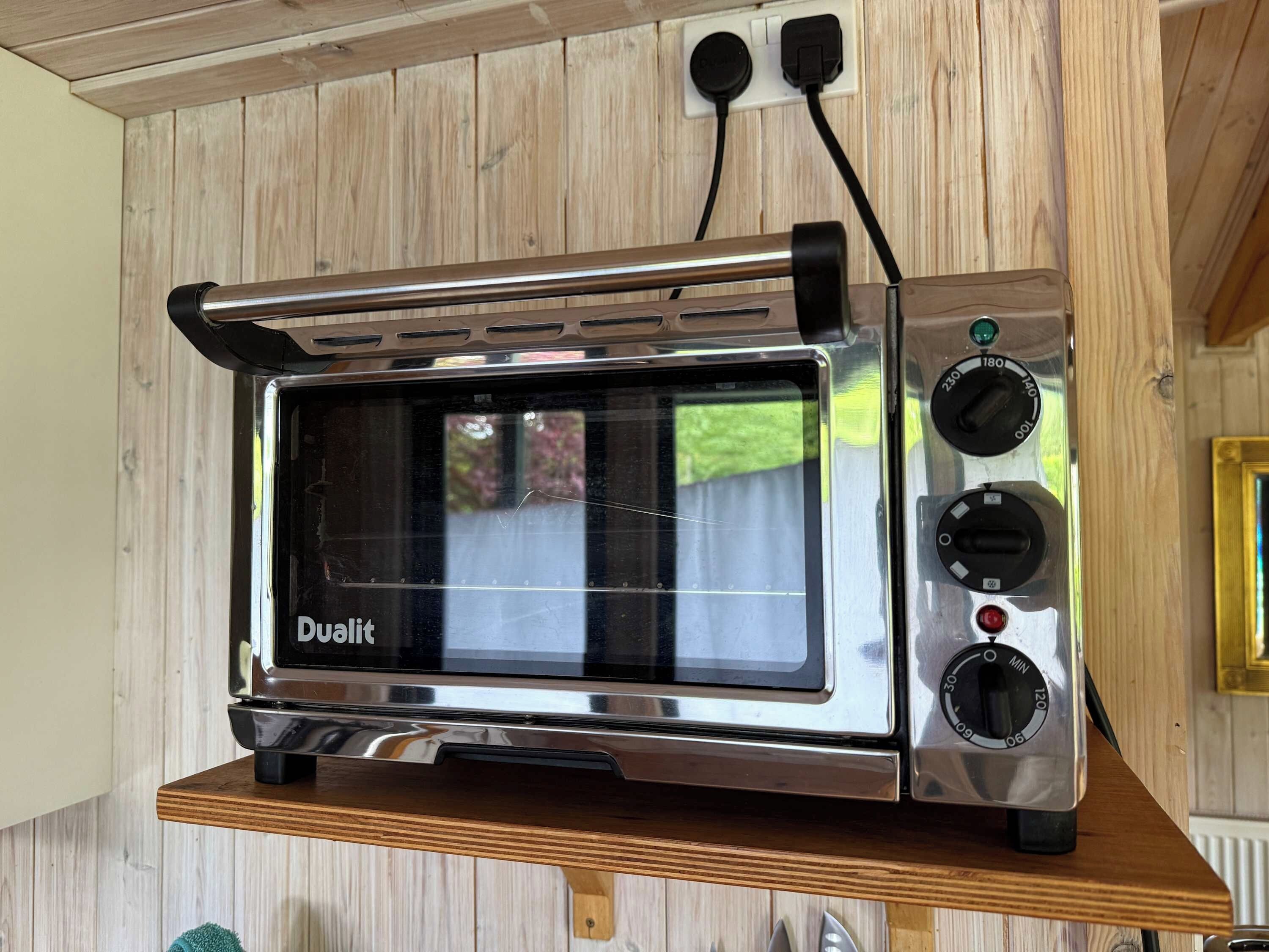 A stainless steel dual oven microwave on a wooden shelf.