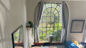 A dining area with a table set for four, a blue sofa, and a window with curtains.