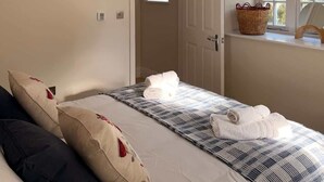 Une chambre à coucher avec un lit, des oreillers, une fenêtre donnant sur un paysage agréable, une porte et un porte-serviettes fixé au mur.