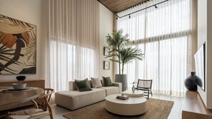 A modern living room with a sofa, coffee table, and dining area. - Unique High-End Loft Apt Cap Cana (Ciudad Las Canas, Cap Cana)