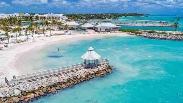 A coastal resort with a white sandy beach, clear turquoise waters, and a rocky pier leading to a gazebo. - Unique High-End Loft Apt Cap Cana (Ciudad Las Canas, Cap Cana)