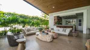 A modern living room with a large sofa, two armchairs, and a coffee table. There is a kitchen area visible in the background. - Unique High-End Loft Apt Cap Cana (Ciudad Las Canas, Cap Cana)