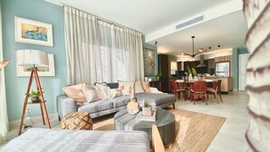 Een moderne woonkamer met een bank, salontafel en een eetgedeelte met stoelen en een tafel.