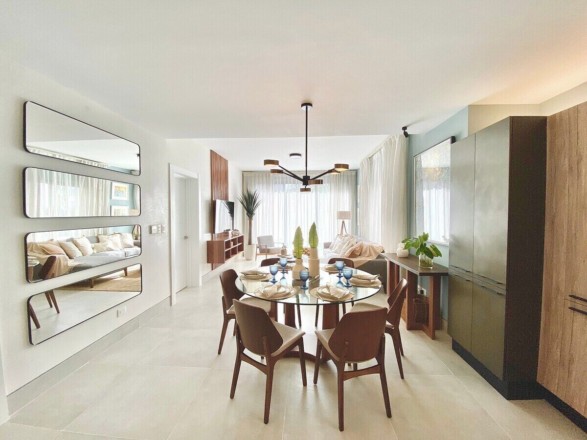 A modern dining area with a round table, chairs, and a chandelier.