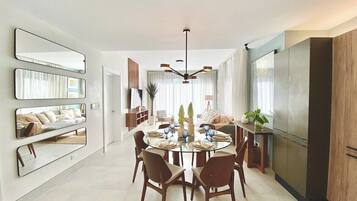 A modern dining area with a round table, chairs, and a chandelier.