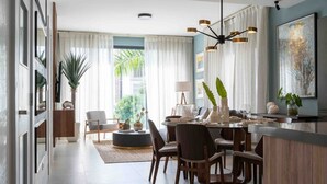 Een moderne eetruimte met een ronde tafel, stoelen en een centraal eiland met een lamp.