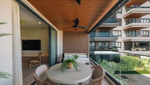 Un balcon avec une table ronde, des chaises, un ventilateur de plafond et une plante en pot.