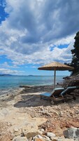 Playa privada, arena negra, sillas reclinables de playa, sombrillas