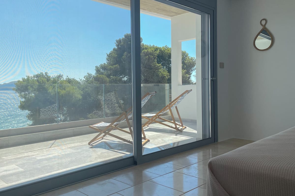 A balcony with a view of the sea, a hammock, and a hanging mirror.