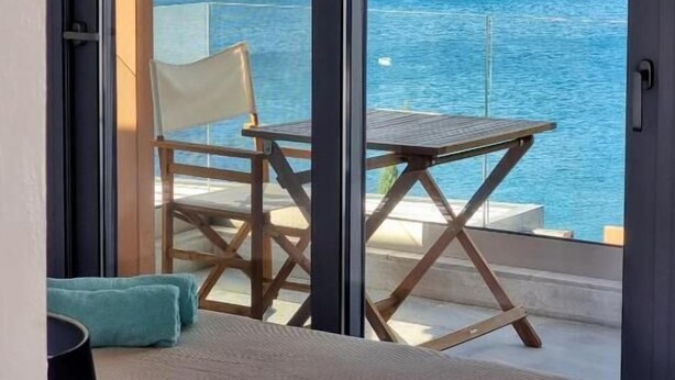 Ein Balkon mit Meerblick, ein Stuhl, ein Tisch und ein Bett.