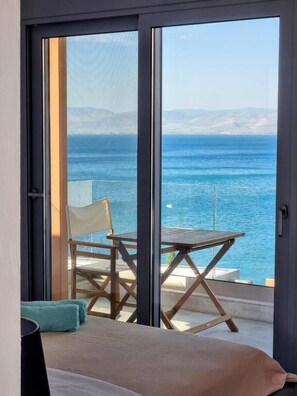 A balcony with a view of the sea, a chair, a table, and a bed. - Anavalos (North Kynouria)