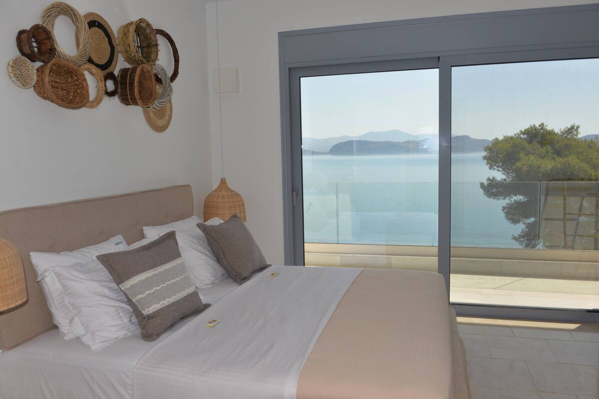 A bedroom with a large bed, a view of the sea, and a balcony.