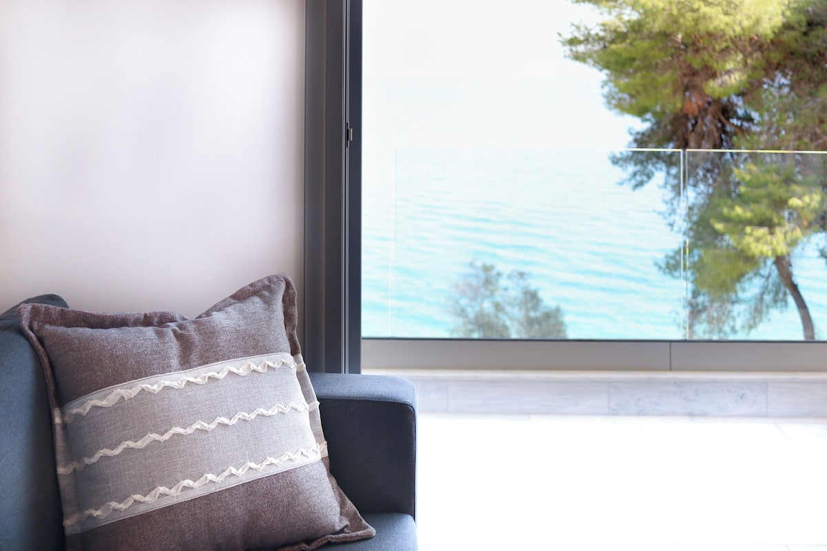 A modern room with a large window, a blue chair, and a decorative pillow.