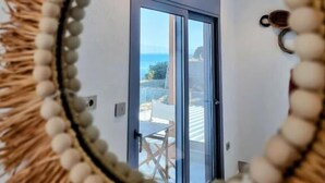 Ein Spiegel mit dekorativem Rahmen, der eine Tür und einen Ausblick ins Freie zeigt.