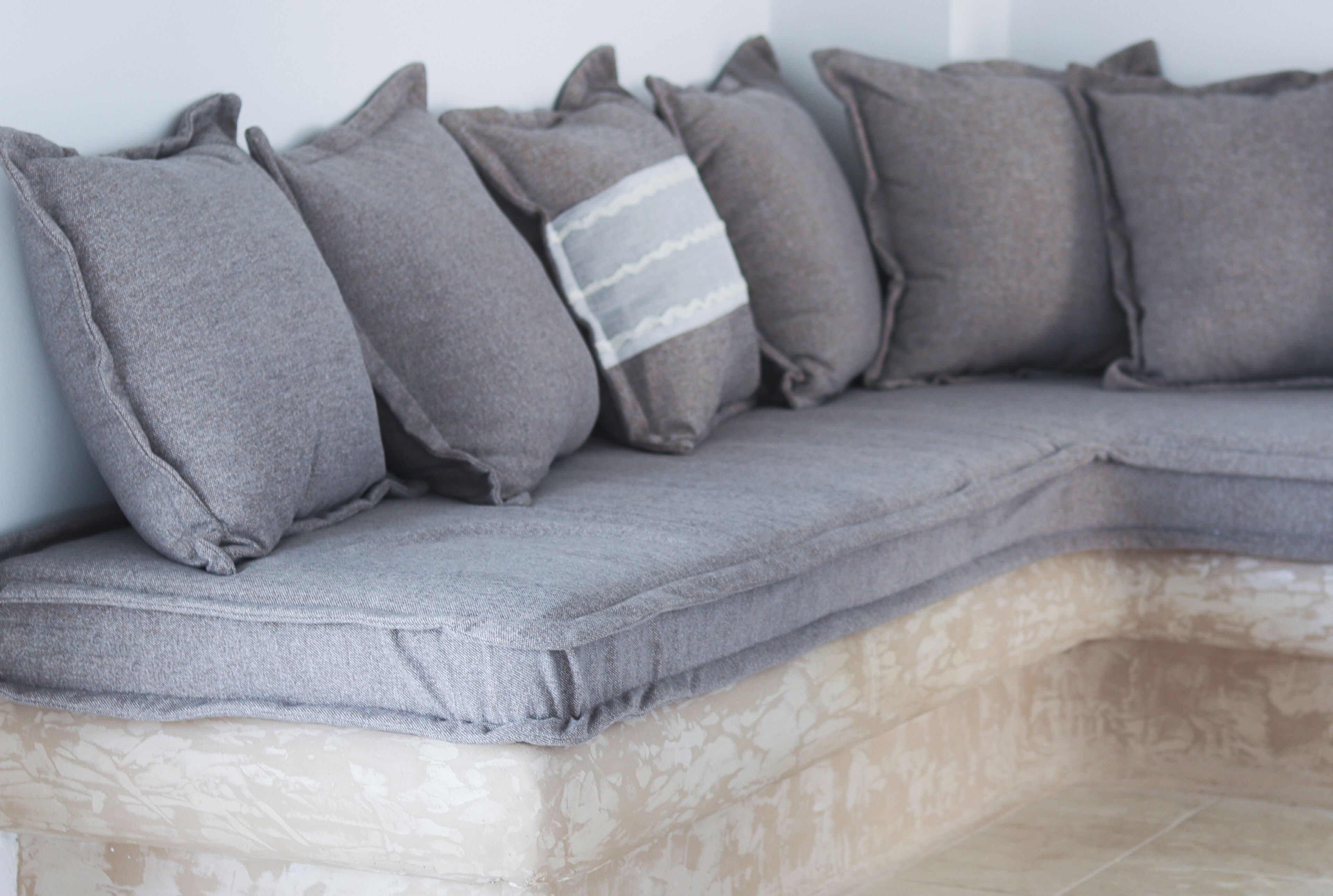 A sectional sofa with a grey fabric and a pillow with a striped pattern.