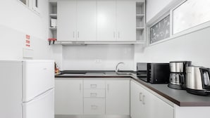 Une cuisine moderne avec des meubles blancs, un réfrigérateur, une machine à café et un four à micro-ondes.