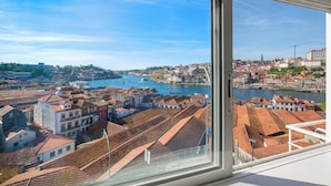 Une vue depuis une fenêtre donnant sur un paysage urbain, avec des bâtiments, une rivière et un pont.