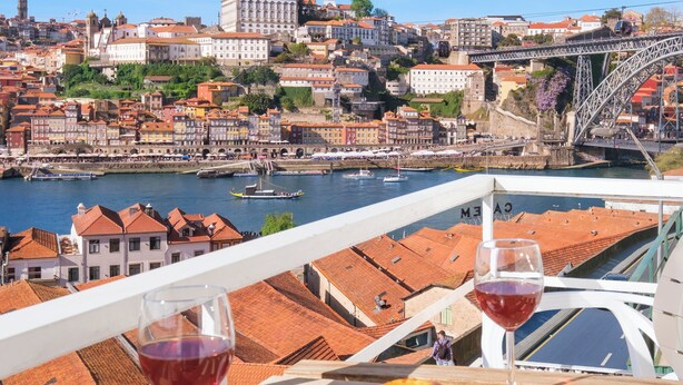 Un balcon avec une table, deux verres de vin rouge et deux pâtisseries.
