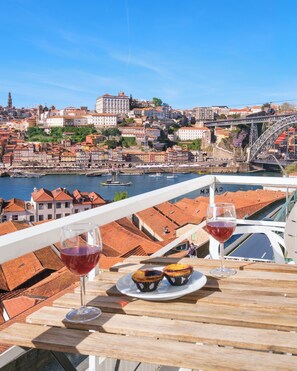Ein Balkon mit Tisch, zwei Gläsern Rotwein und zwei Gebäckstückchen.