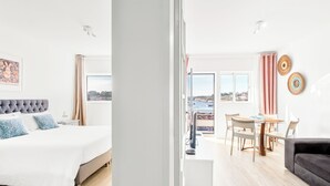 Une chambre d’hôtel moderne, équipée d’un lit, d’un coin repas et offrant une vue sur la ville.