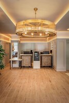 A modern kitchen with a central chandelier, wooden cabinets, and a built-in coffee machine.