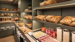 A buffet area with various food items, including breads, meats, and condiments. - B&B HOTEL Madrid Vallecas Ensanche (Madrid)