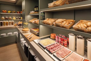 A buffet area with various food items, including breads, meats, and condiments.
